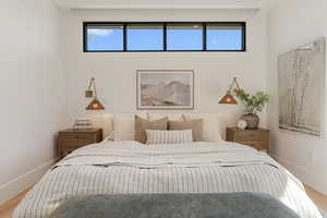 Bedroom with wood finished floors and multiple windows