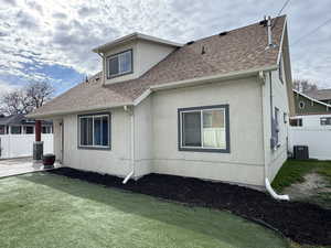 Back of property featuring a shingled roof and stucco siding