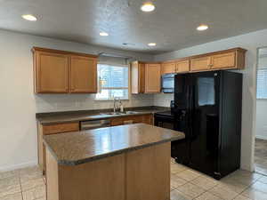 Kitchen featuring dark countertops, black appliances, recessed lighting, a kitchen island, and light tile patterned floors