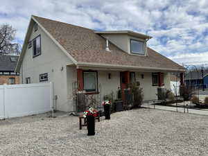 View of front facade featuring a shingled roof and stucco siding