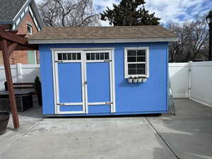 View of shed with a fenced backyard and a gate