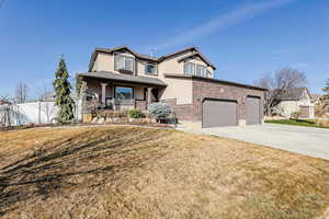 View of front of house featuring stucco siding, a porch, driveway, and brick siding