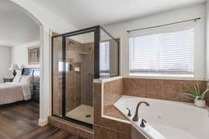 Ensuite bathroom with a tub with jets, a stall shower, and dark wood-type flooring