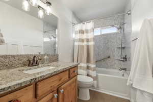 Bathroom featuring vanity, shower / tub combo with curtain, and dark tile patterned floors
