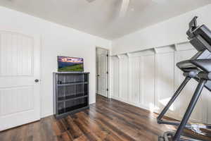 Exercise area featuring dark wood-type flooring, ceiling fan, and a textured ceiling