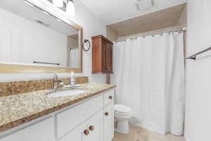 Full bathroom featuring vanity, curtained shower, and light tile patterned flooring