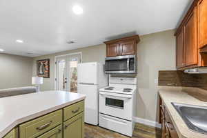 Kitchen with white appliances, light countertops, dark wood finished floors, recessed lighting, and green cabinetry