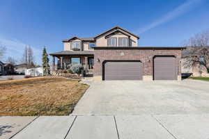 View of front of house featuring a porch, a front yard, stucco siding, driveway, and brick siding