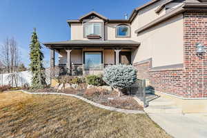 View of front of house featuring stucco siding, a porch, and brick siding
