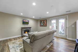 Living area featuring dark wood-style flooring, a fireplace, recessed lighting, and french doors
