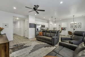 Living room featuring ceiling fan, light wood-type flooring, and a chandelier