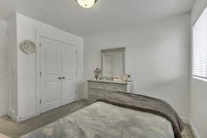 Bedroom with light colored carpet and a closet