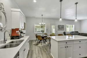 Kitchen featuring white cabinets, light wood-style floors, open floor plan, suspended lighting, and a kitchen bar