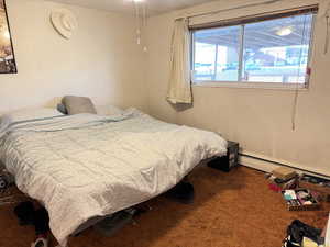 Carpeted bedroom featuring a baseboard heating unit