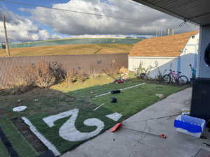 View of grassy yard featuring a patio and a shed