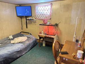 Carpeted bedroom featuring wood walls