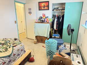 Carpeted bedroom featuring a baseboard radiator and a closet