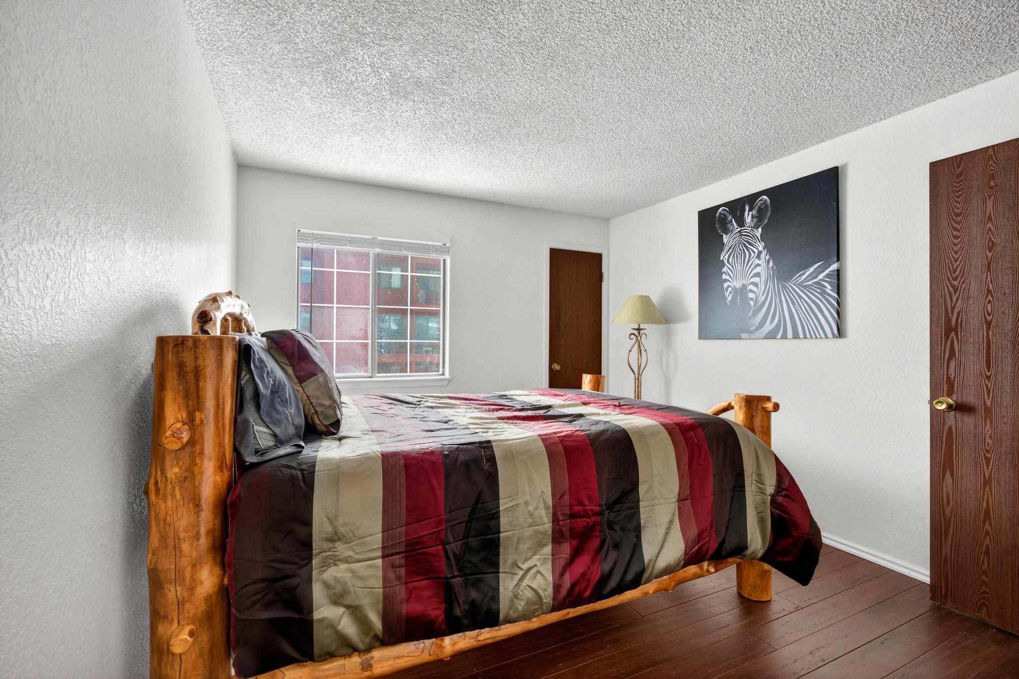 Bedroom featuring a textured ceiling, hardwood / wood-style floors, and a textured wall