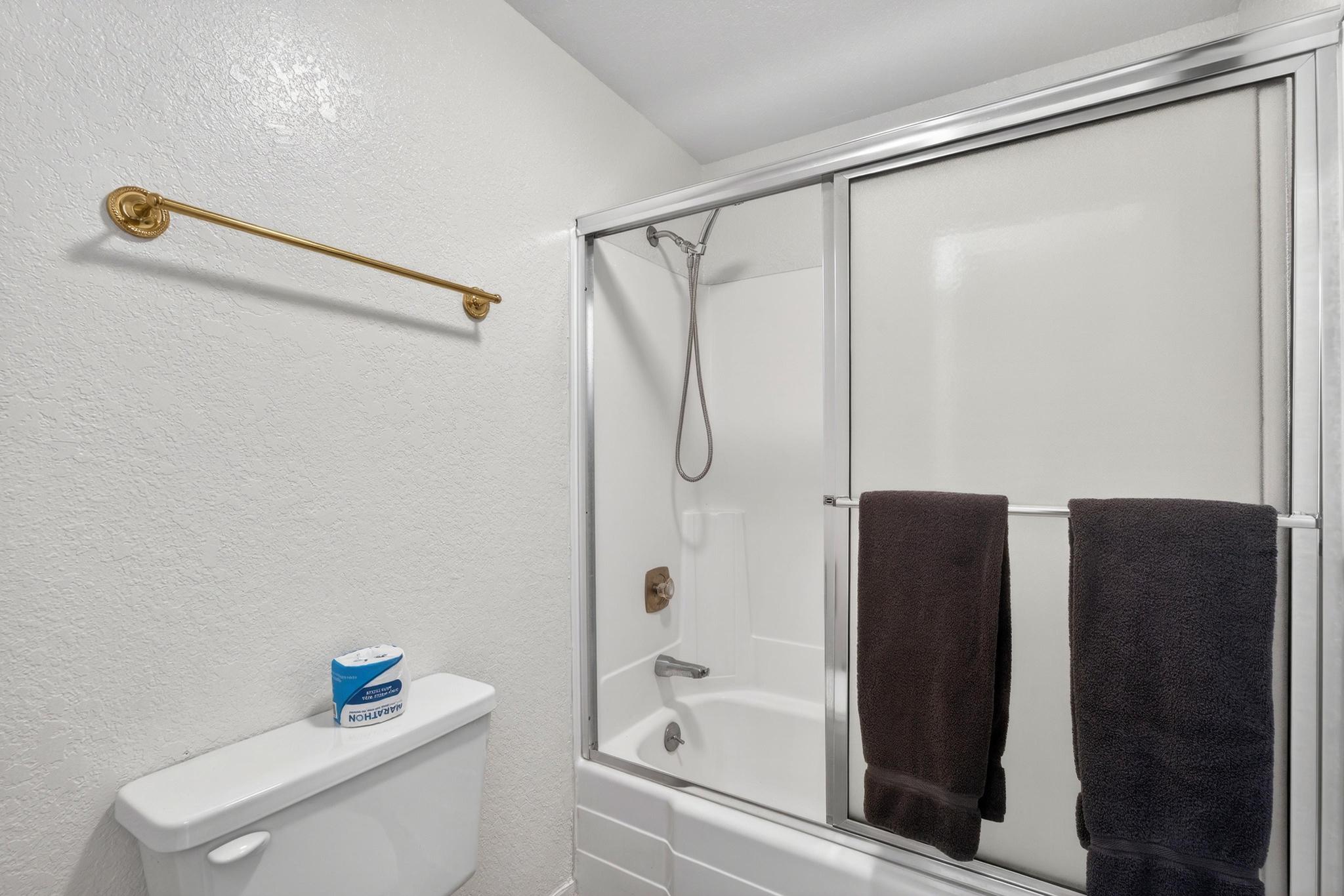 Bathroom with a textured wall and enclosed tub / shower combo