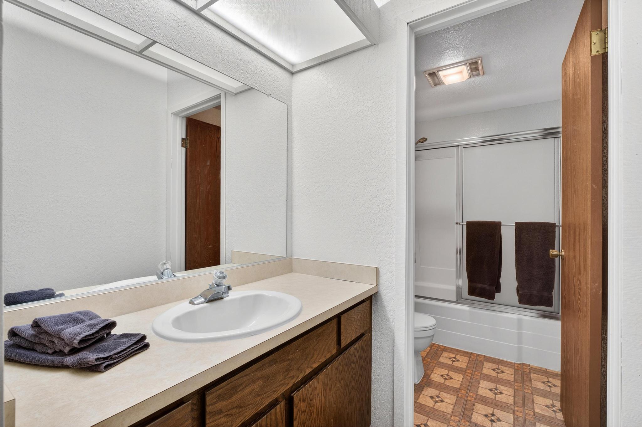 Bathroom with combined bath / shower with glass door, a textured wall, vanity, light flooring, and a textured ceiling