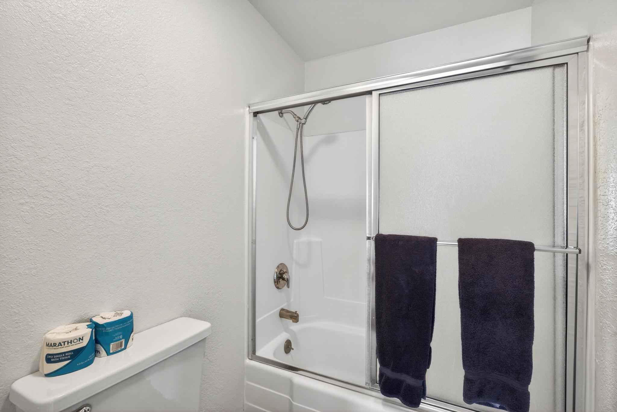 Full bath with a textured wall and combined bath / shower with glass door