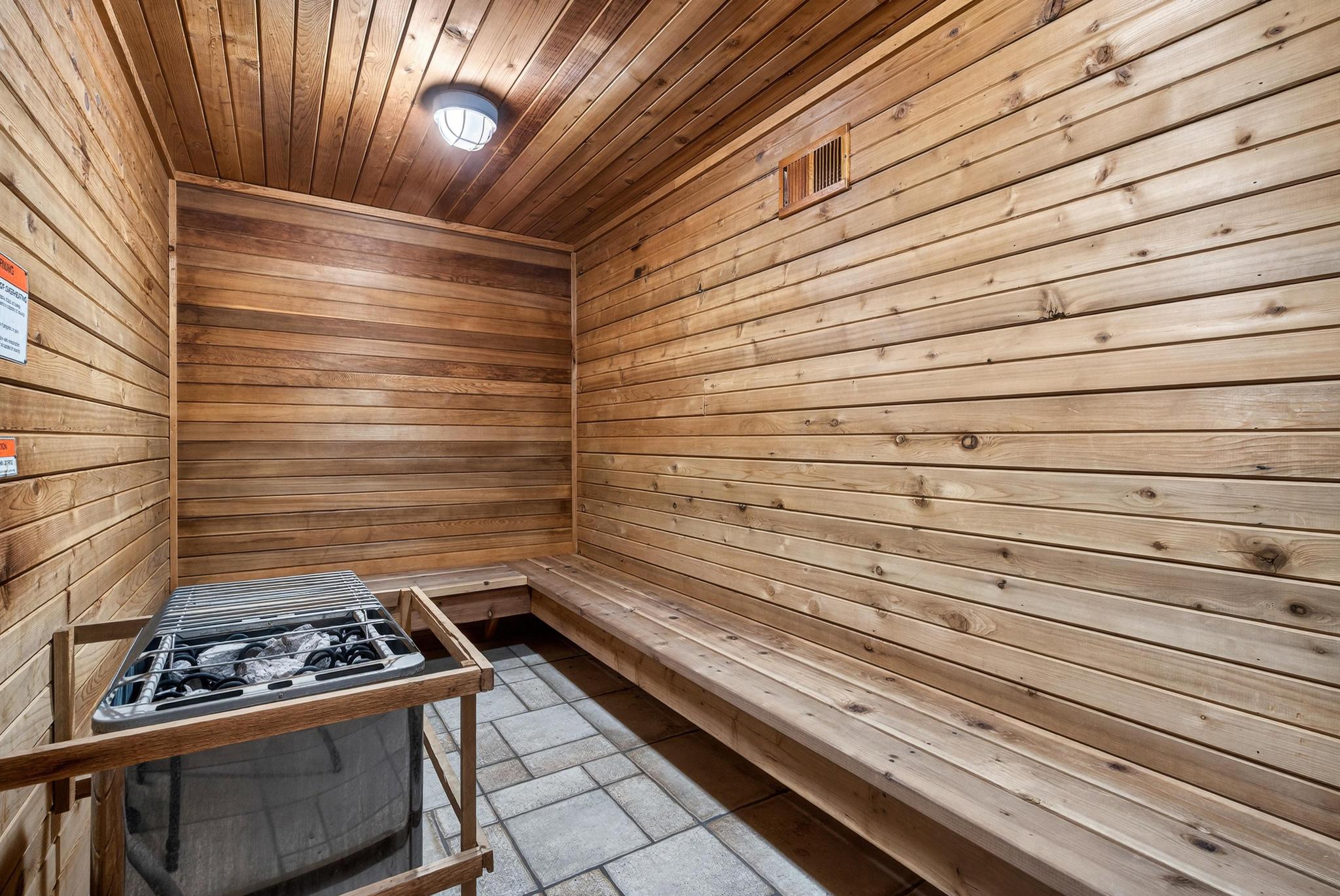 Sauna / steam room with wooden walls, wooden ceiling, and stone tile flooring