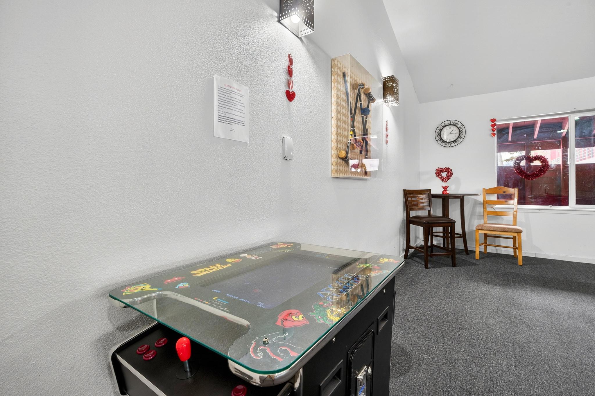Game room featuring lofted ceiling, dark colored carpet, and a textured wall