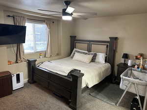 Carpeted bedroom with a textured ceiling and ceiling fan