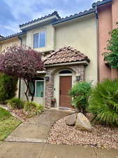 View of front of property with stucco siding, stone siding, and a tile roof