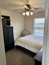 Carpeted bedroom featuring a textured ceiling and a ceiling fan