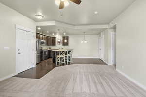 Living room featuring a ceiling fan, suspended lighting, and dark wood-style floors