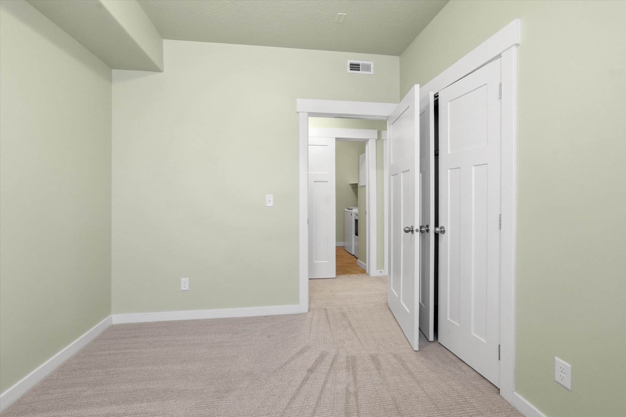 Secondary bedroom with light carpet and baseboards
