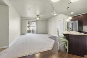Kitchen with a kitchen bar, open floor plan, dark wood finish cabinets, pendant lighting, and stainless steel fridge