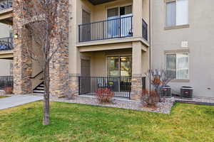 Entrance to property with stucco siding, stone siding, and a lawn