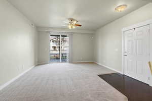 Carpeted living room with ceiling fan and sliding glass door to covered patio.