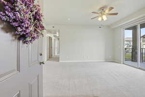 Living room featuring light carpet, ceiling fan, and sliding glass door to patio.