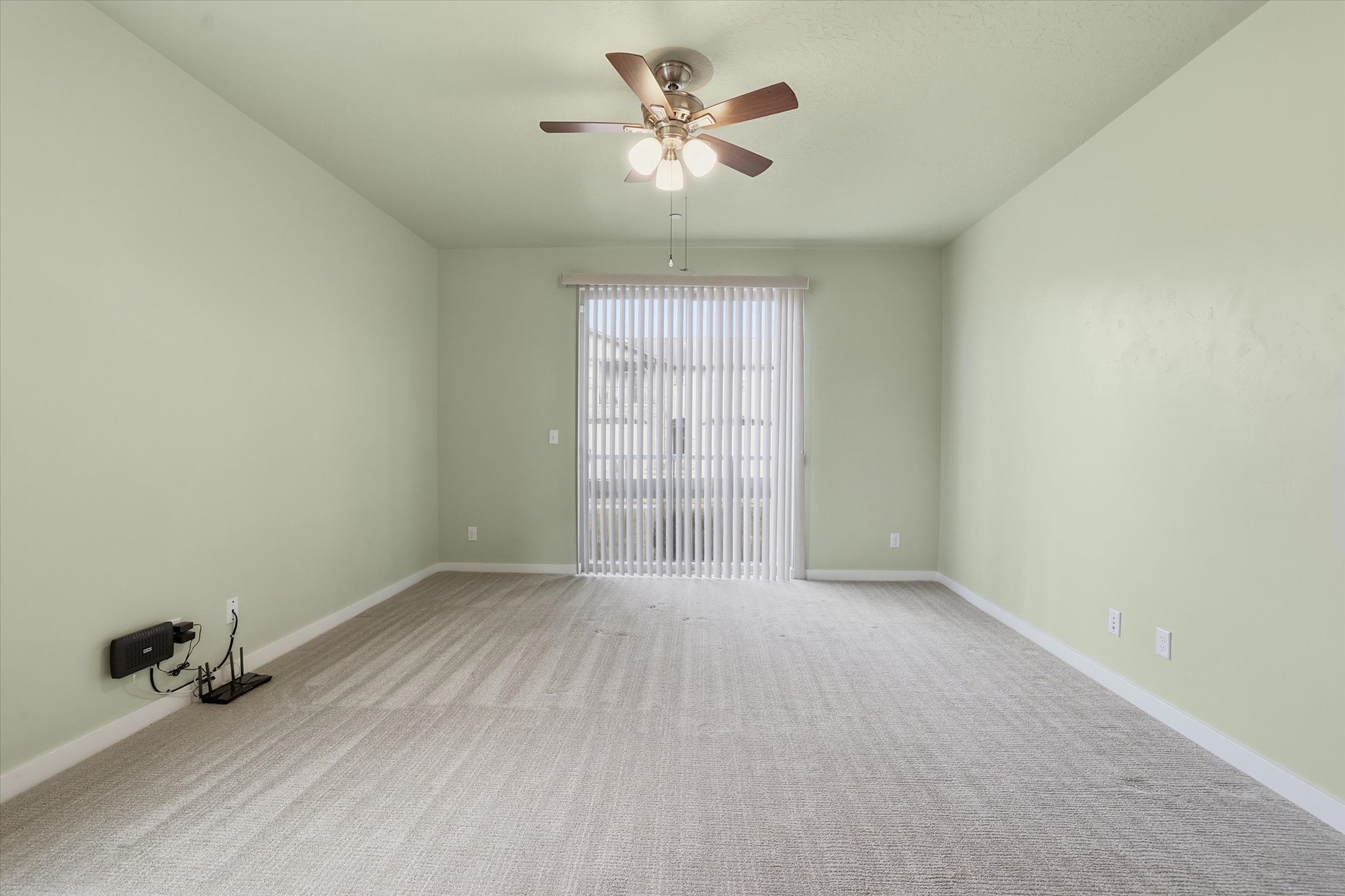 Primary bedroom suite with a spacious walk-in closet, light colored carpet, ceiling fan, and ensuite bath