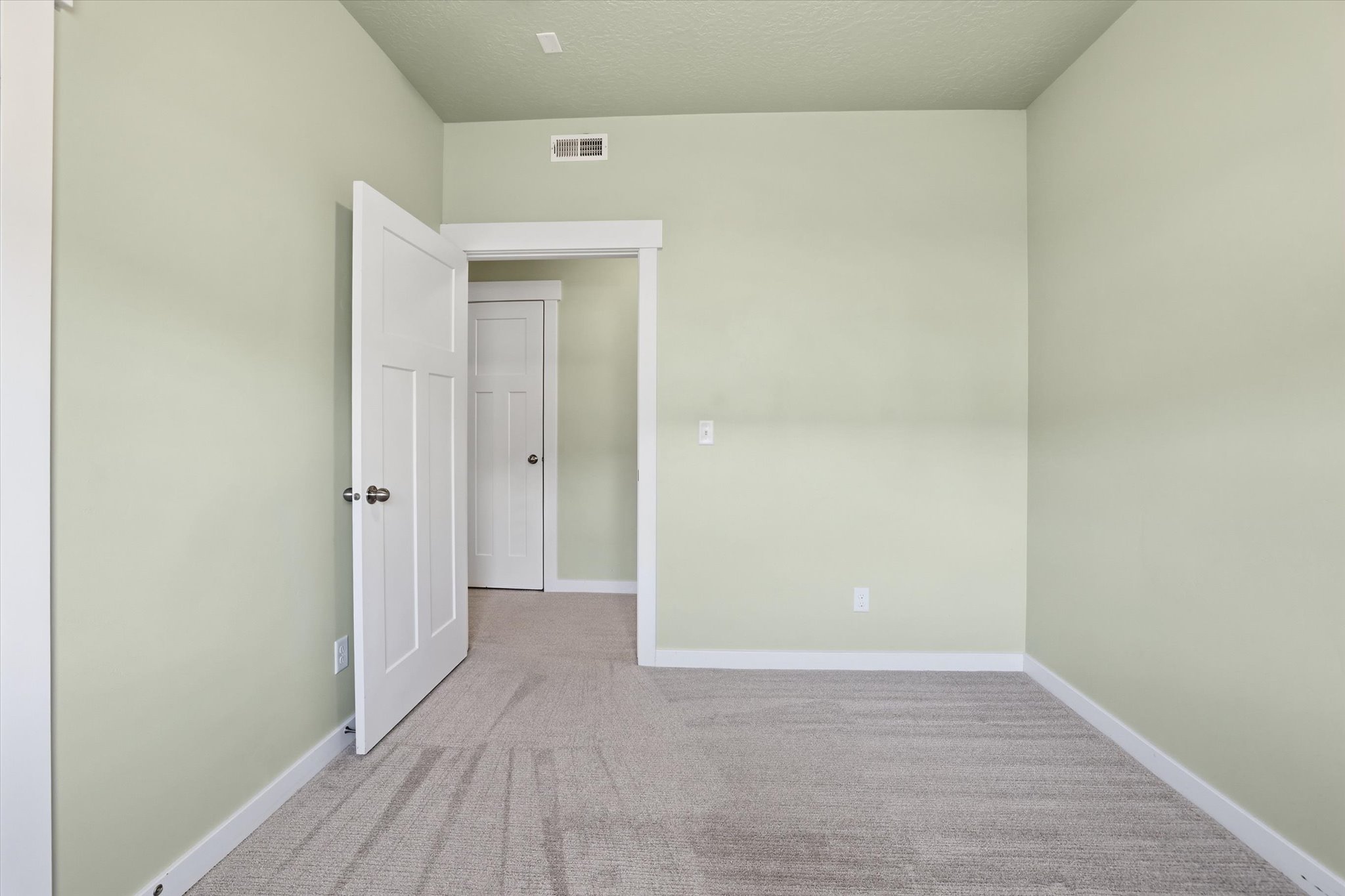 Secondary bedroom with light colored carpet and a textured ceiling