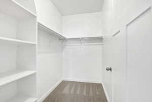 Walk in closet with carpet flooring and storage - located in the Primary bedroom suite.