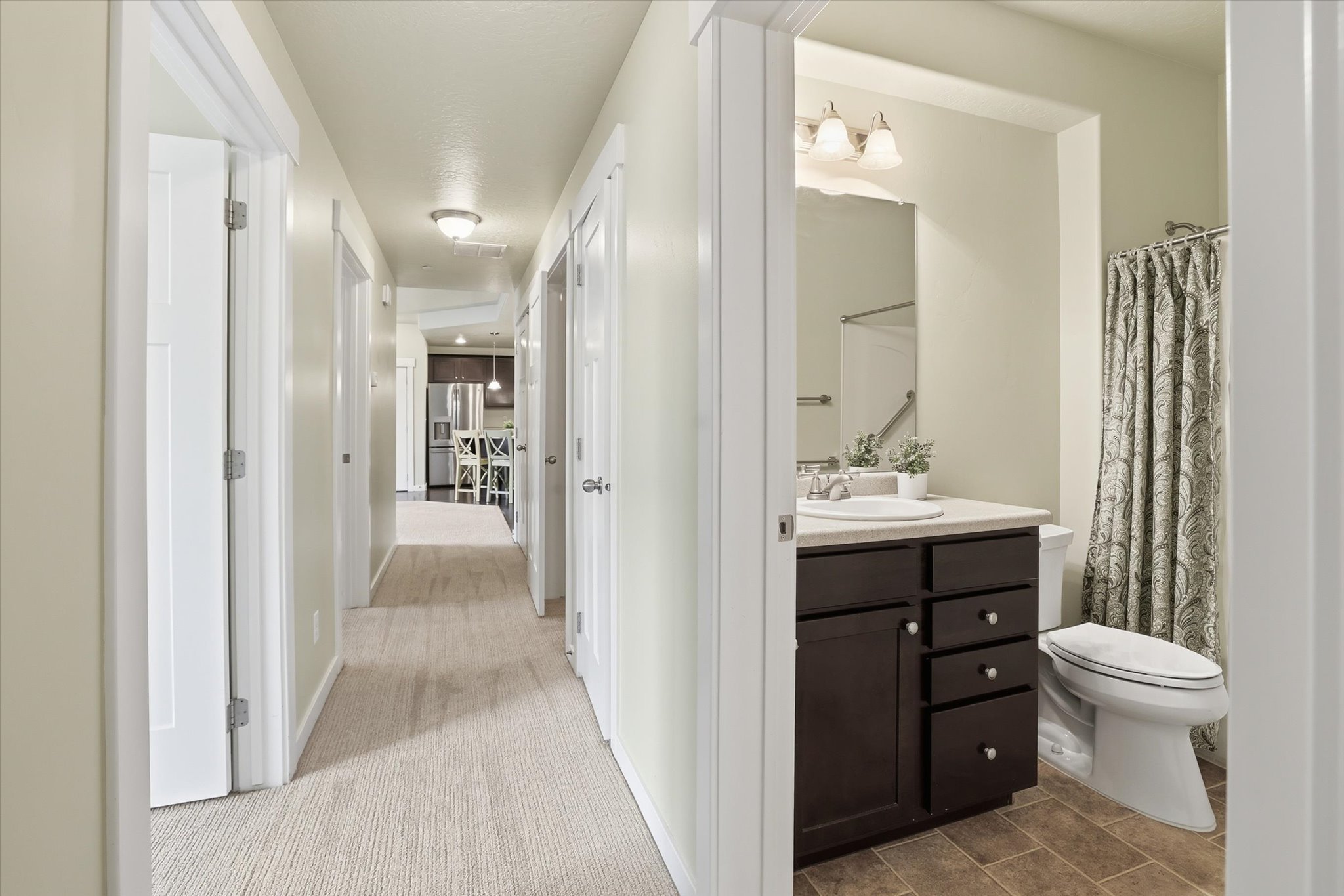 Hall featuring light carpet, baseboards, and access to hall closet,  main full bathroom, and 3 bedrooms