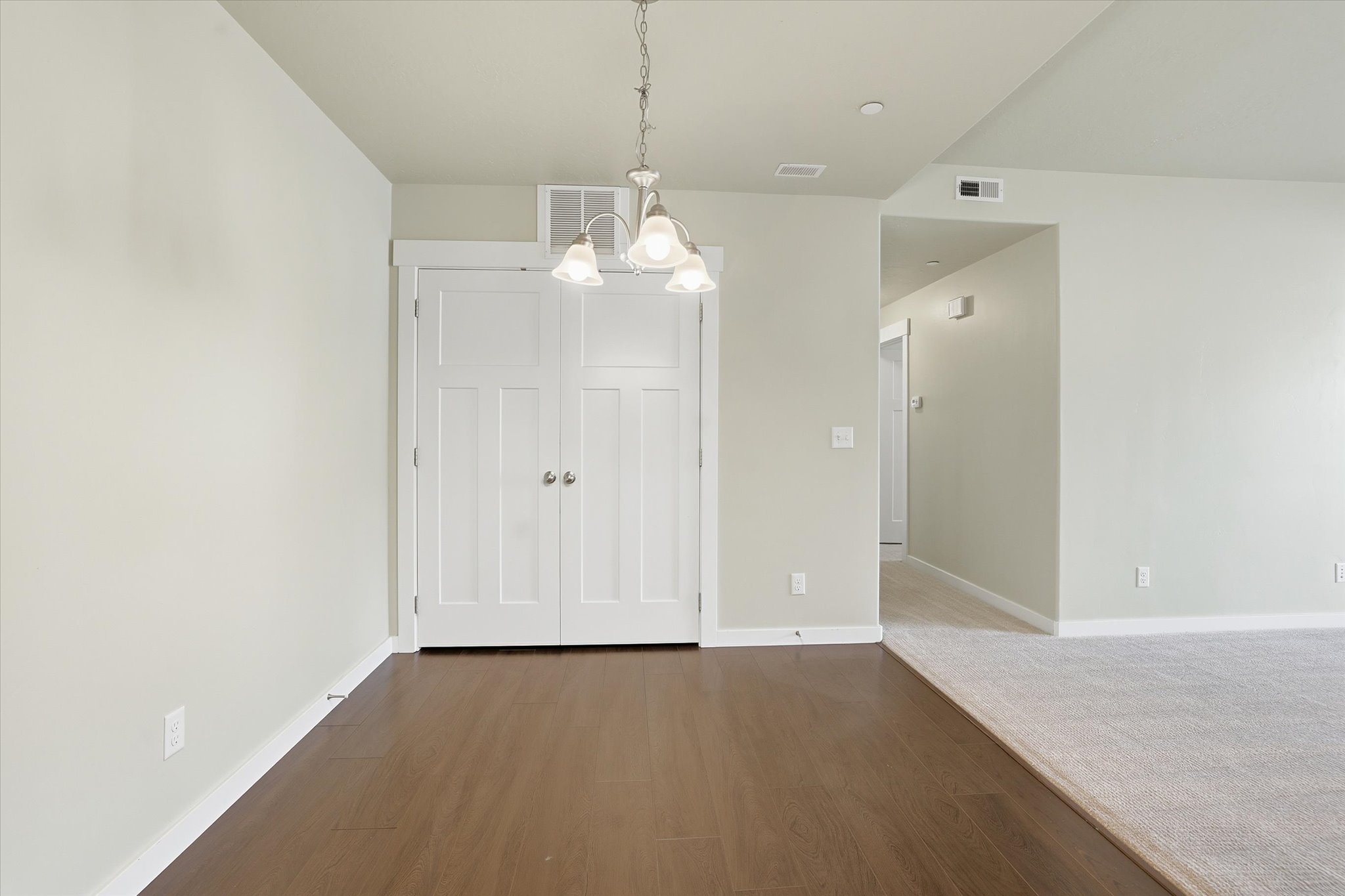 Unfurnished dining area with hanging lights and dark wood-style floors and large pantry closet