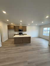 Kitchen featuring recessed lighting, light countertops, light wood finished floors, stainless steel appliances, and wood finish cabinets