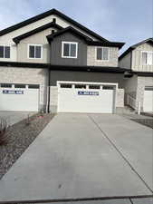 View of front of house featuring stone siding, driveway, and a garage