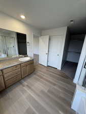 Full bathroom featuring vanity, a stall shower, light wood-style floors, a spacious closet, and a bathtub