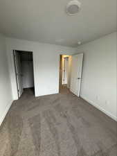 Unfurnished bedroom with a spacious closet and carpet