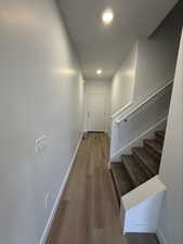 Stairs with wood finished floors and recessed lighting