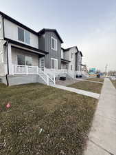 Back of house featuring stone siding, a lawn, a porch, and board and batten siding
