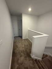 Corridor featuring dark carpet, an upstairs landing, and recessed lighting