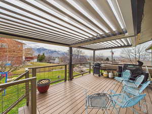 Deck featuring a lawn, a mountain view, and grilling area with pergola