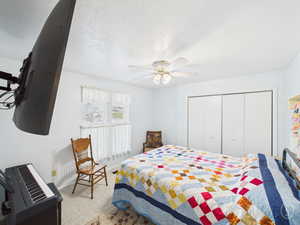 Bedroom featuring a textured ceiling, a closet, ceiling fan, and carpet floors